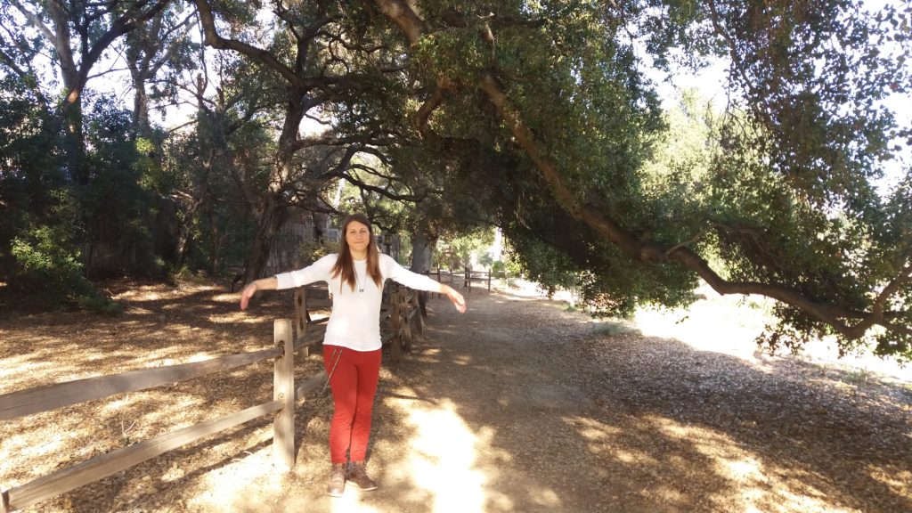 Photo of Notes of Oak Blog Writer Hannah Huff beside oak tree in Descanso Gardens, a SoCal Literary Landmark