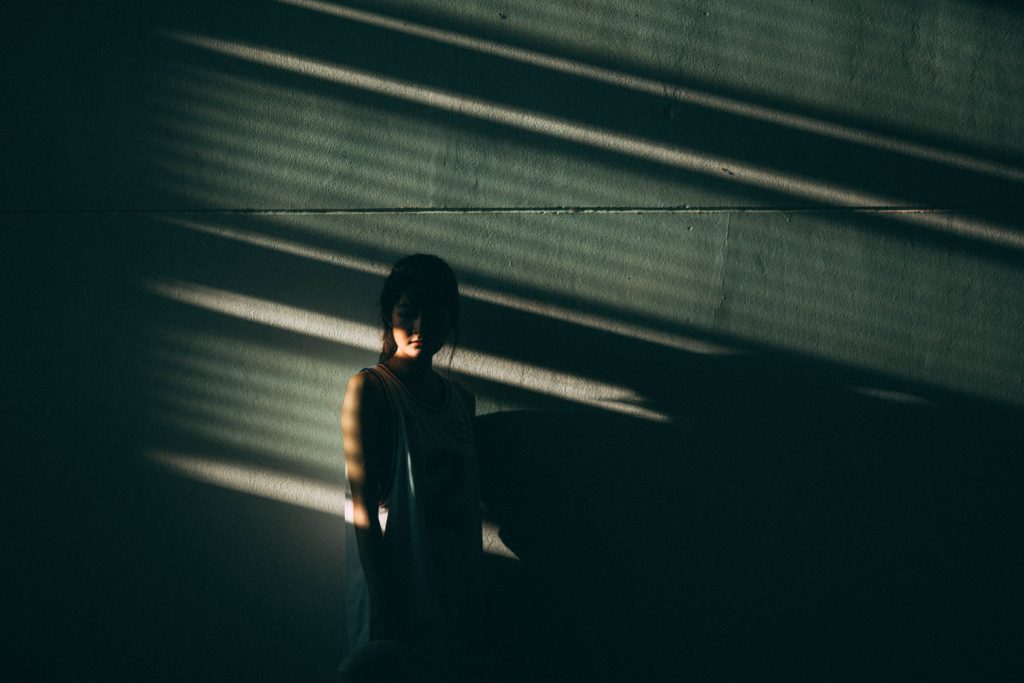 Photo of person in shadows to represent creative book title of The Unbearable Lightness of Being by Milan Kundera