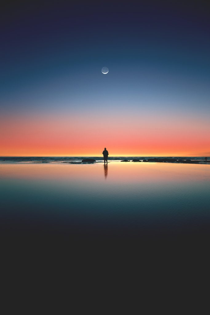 Photo of the moon rising above a beach and a poet.