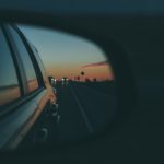 A photo of a rearview mirror on a car representing travel poetry