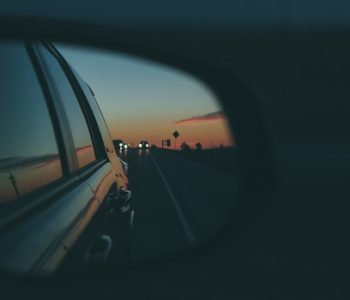 A photo of a rearview mirror on a car representing travel poetry
